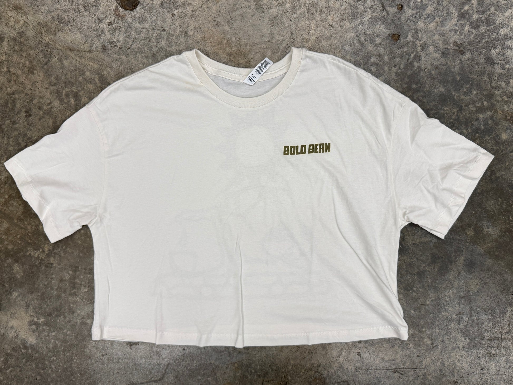 White t-shirt with 'bold bean' text on a textured surface