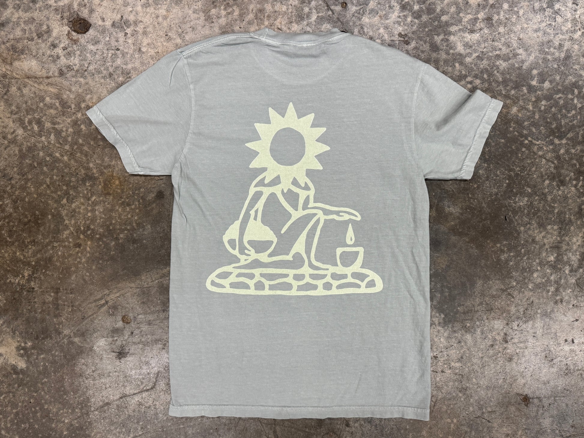 Gray t-shirt with a white graphic design on a textured surface