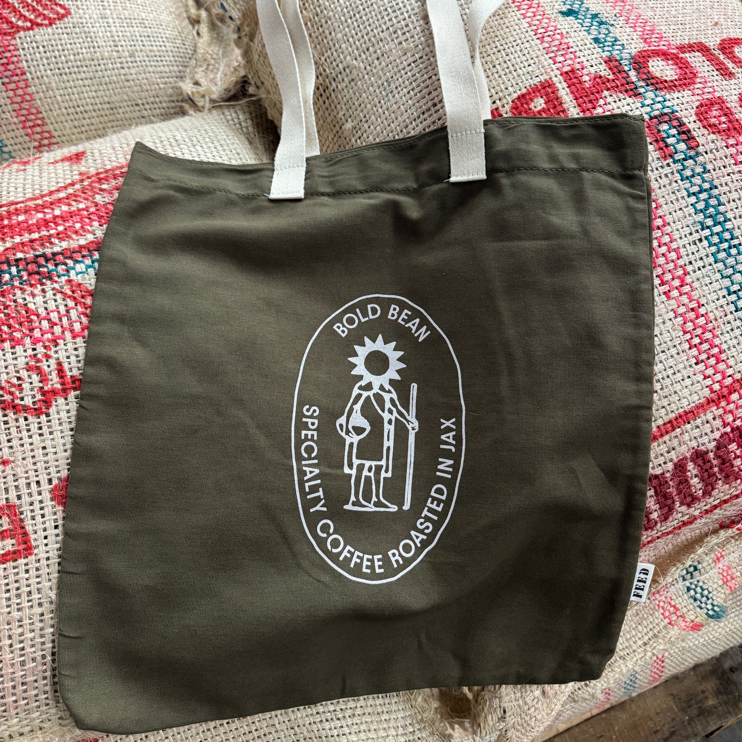 Green tote bag with a coffee roaster logo on a textured surface