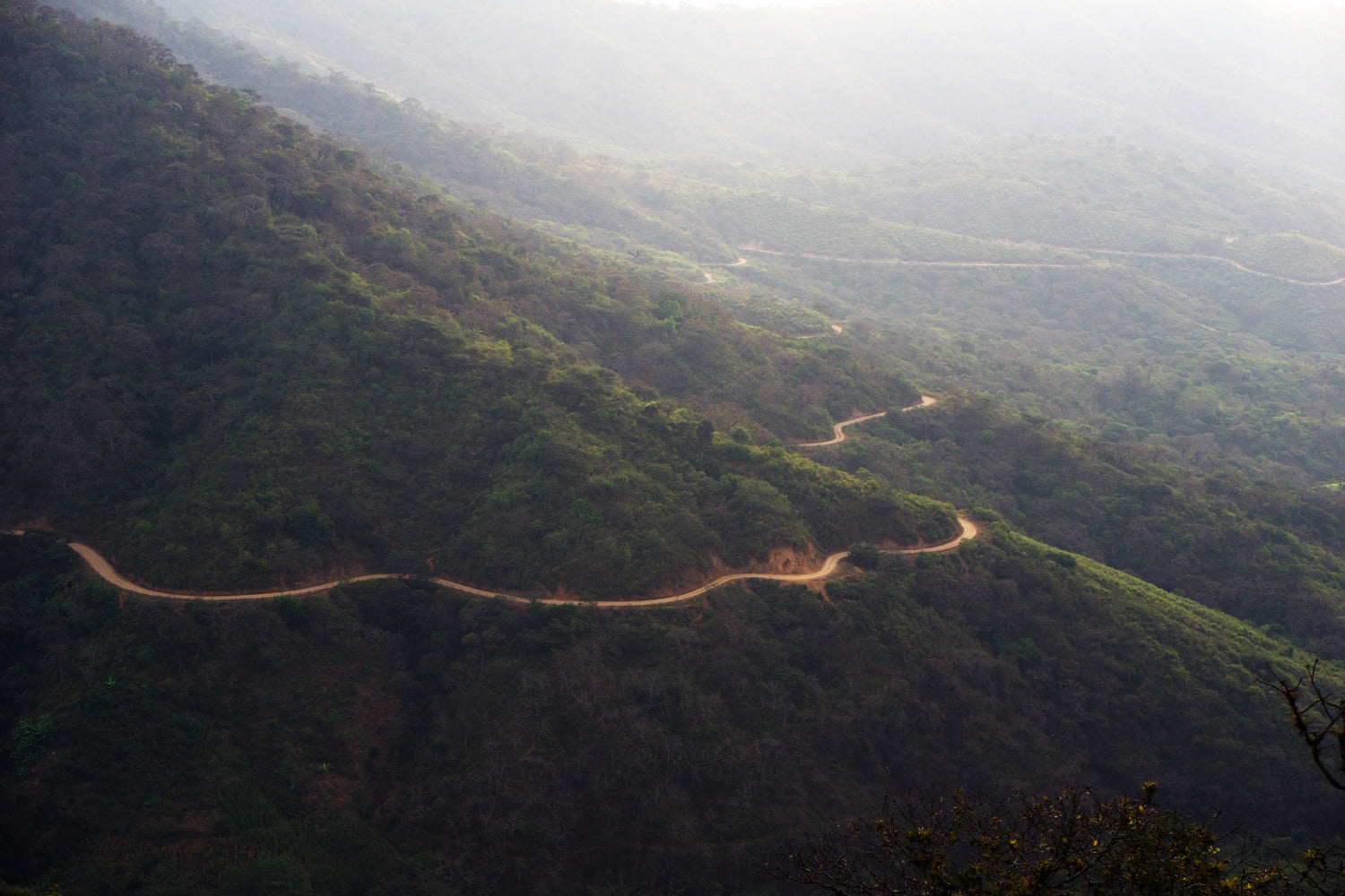 a winding dirt road through the mountains of rural Peru