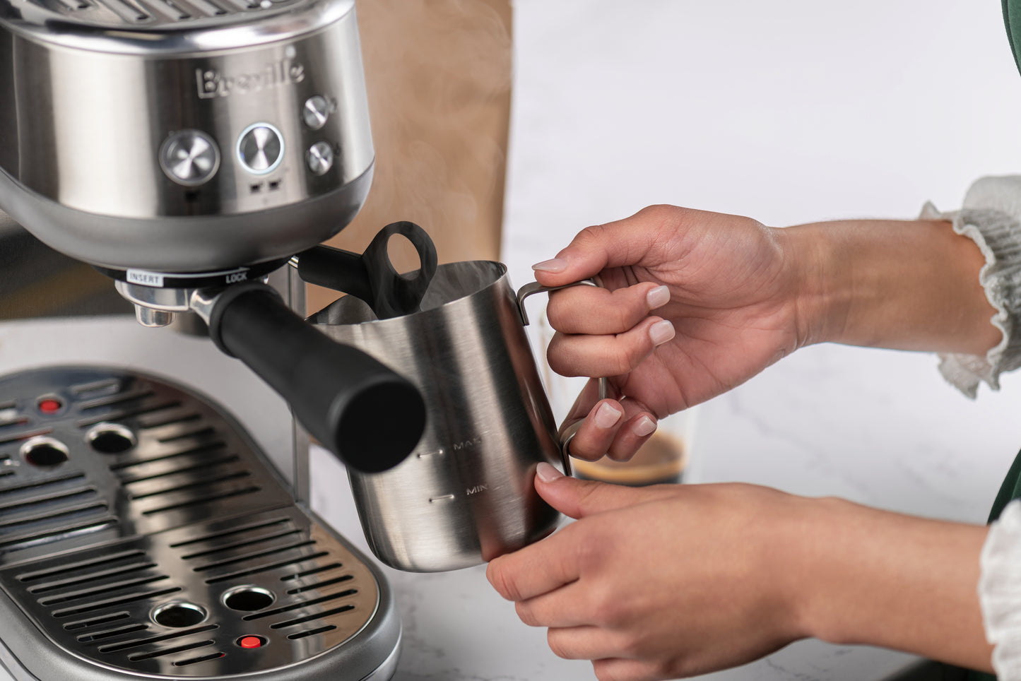image of espresso machine and person steaming milk in pitcher