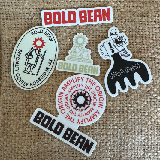 Collection of 'Bold Bean' branded stickers on a textured fabric background