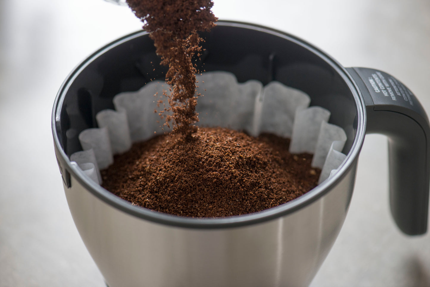 image of coffee grounds being poured into filter basket