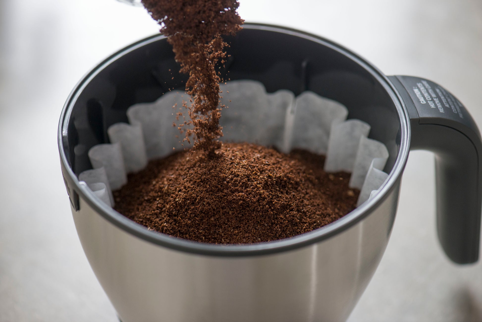 image of coffee grounds being poured into filter basket