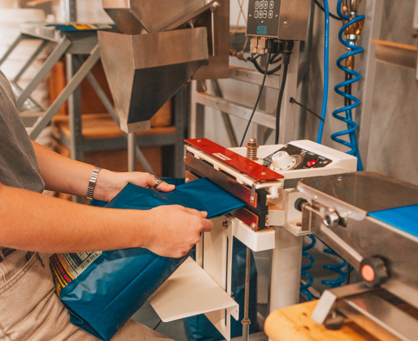 coffee bag being sealed with a sealer and other packaging equipment in background