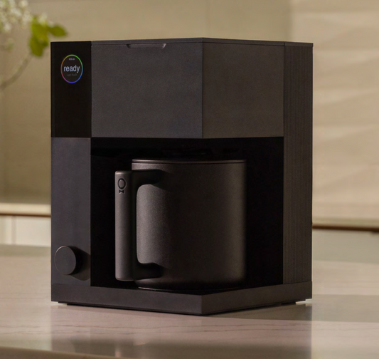 Black coffee maker with a mug on a wooden surface