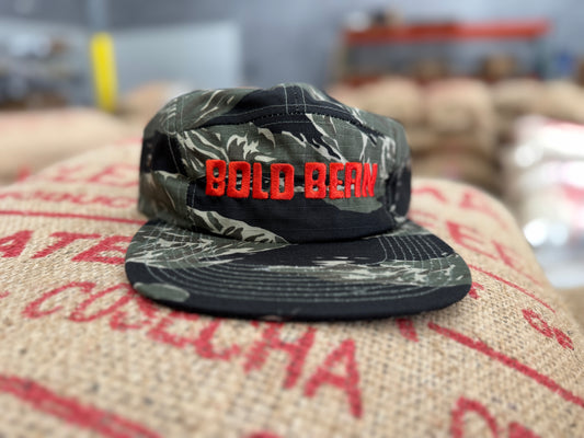 Camouflage cap with 'BOLD BEAN' text on a coffee sack background